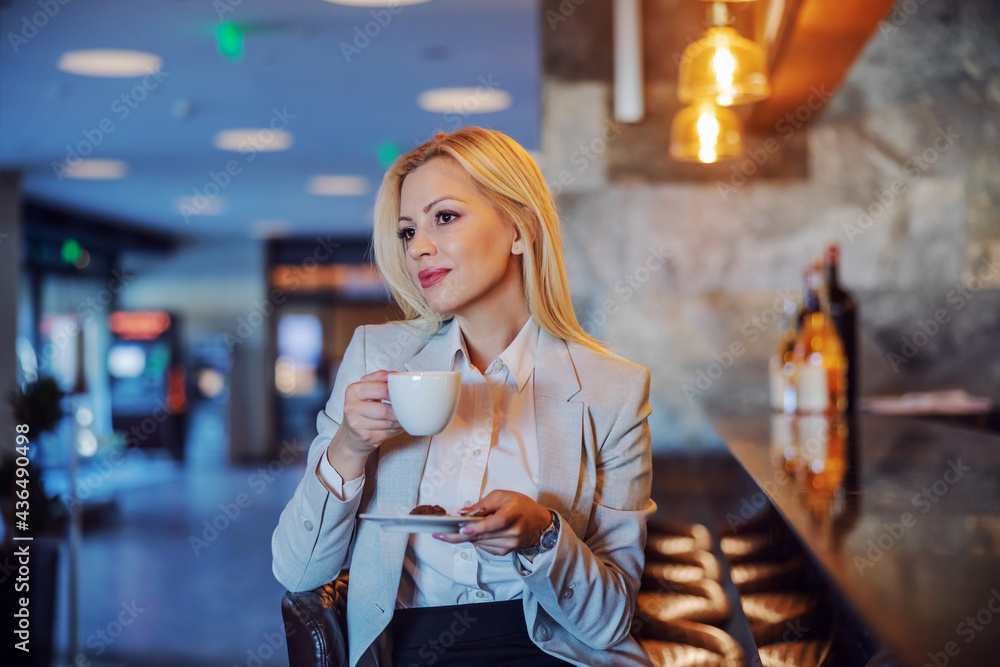 Φωτογραφία Middle-aged professional blonde sitting in the cafe of a hotel and holding a white cup of coffee