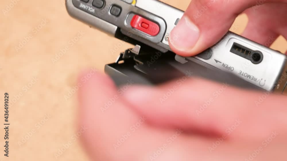 Man replacing an small audio disc cassette, retro voice recorder, hands closeup detail. Changing cassettes, taking out old one, putting in inserting a new one. Portable sound recording device concept Man replacing an small audio disc cassette, retro voice recorder, hands closeup detail. Changing cassettes, taking out old one, putting in inserting a new one. Portable sound recording device concept