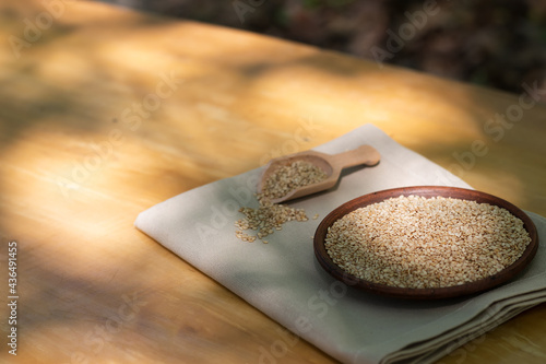 Brown sesame seeds in a clay bowl on a wooden table. photo