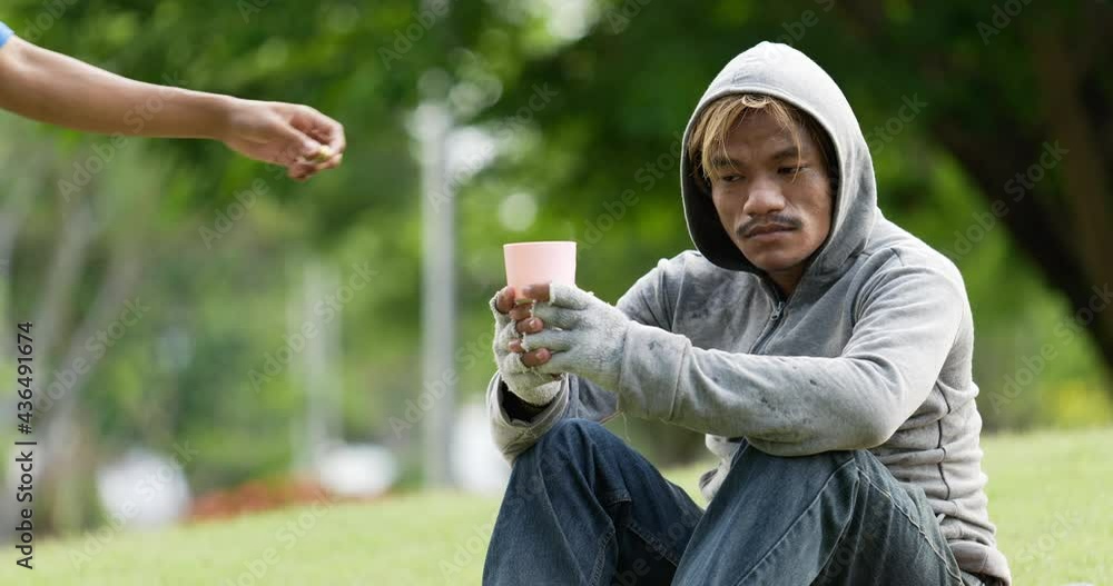 Beggar man sitting on grass and holding a glass asking for money. Beggar man sitting on grass and holding a glass asking for money.