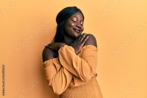 African young woman wearing casual clothes hugging oneself happy and positive, smiling confident. self love and self care photo