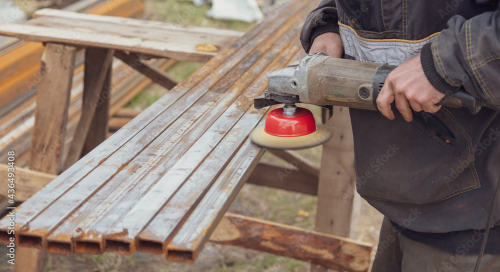 A worker grinds metal at a construction site. A worker grinds metal at a construction site.