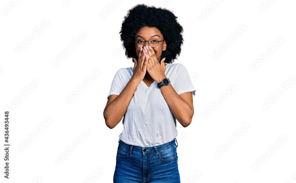 Young african american woman wearing casual white t shirt laughing and embarrassed giggle covering mouth with hands, gossip and scandal concept Young african american woman wearing casual white t shirt laughing and embarrassed giggle covering mouth with hands, gossip and scandal concept