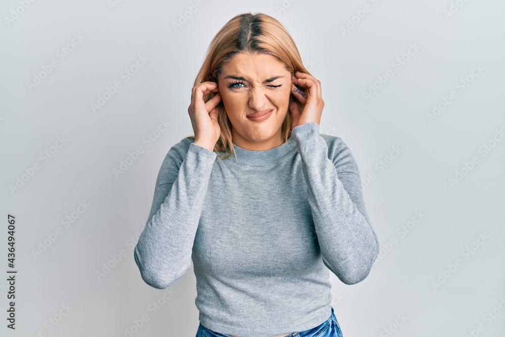 Young caucasian woman wearing casual clothes covering ears with fingers with annoyed expression for the noise of loud music. deaf concept. Young caucasian woman wearing casual clothes covering ears with fingers with annoyed expression for the noise of loud music. deaf concept.