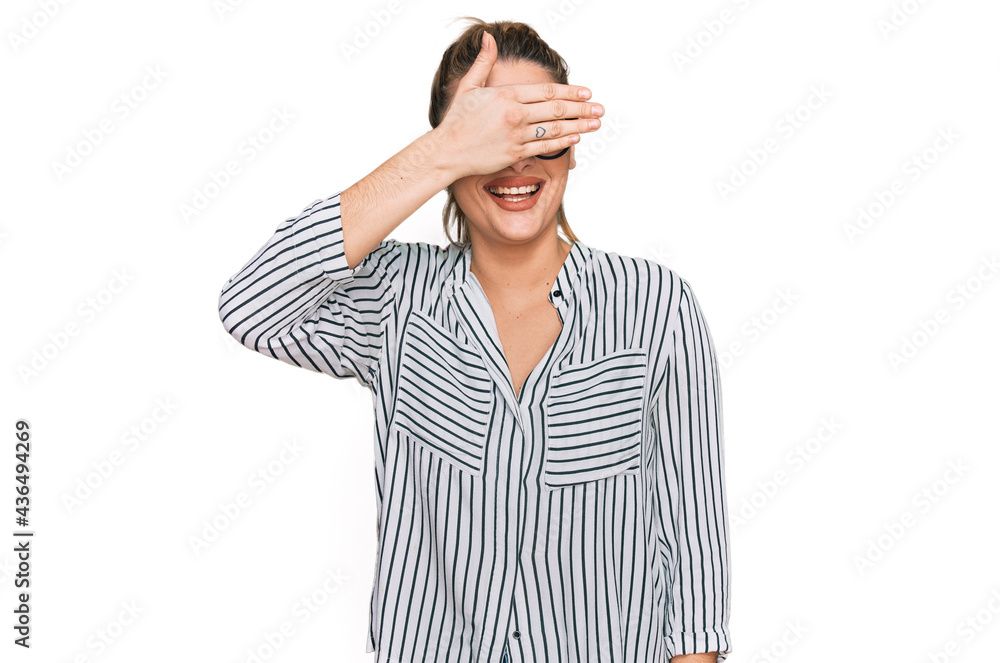 Young caucasian woman wearing business shirt and glasses smiling and laughing with hand on face covering eyes for surprise. blind concept. Young caucasian woman wearing business shirt and glasses smiling and laughing with hand on face covering eyes for surprise. blind concept.