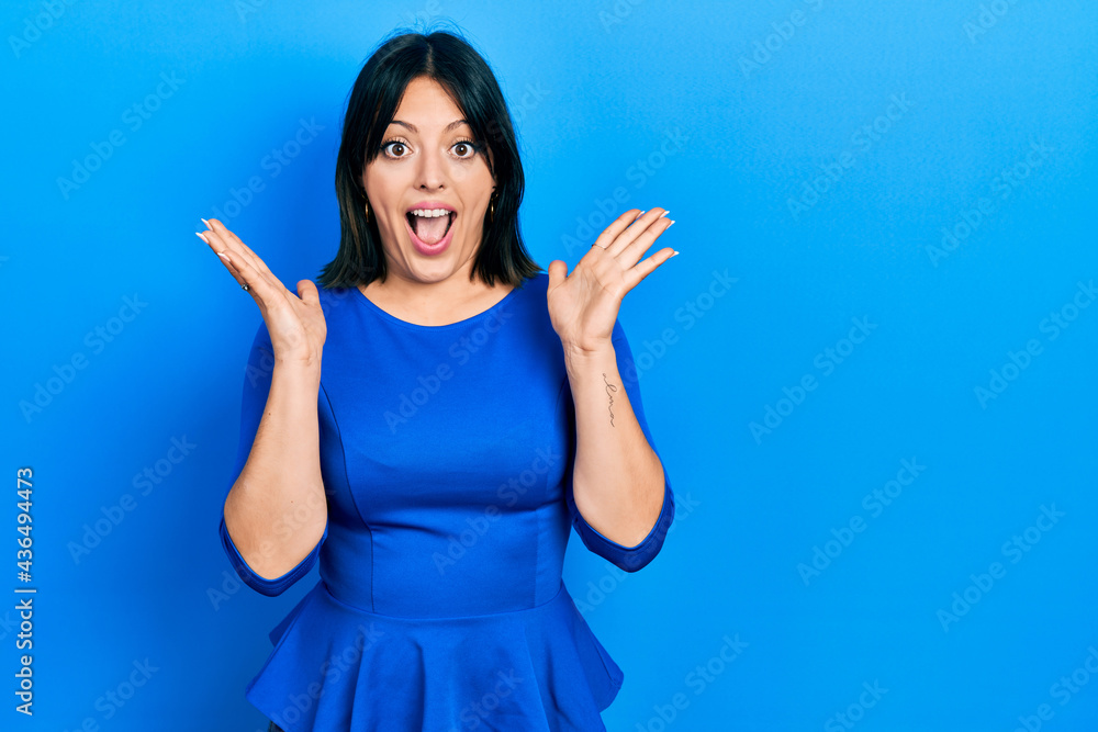 Fototapeta premium Young hispanic woman wearing casual clothes celebrating crazy and amazed for success with arms raised and open eyes screaming excited. winner concept