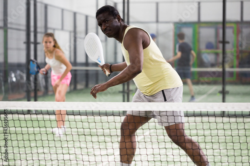 African american man playing paddle tennis indoors