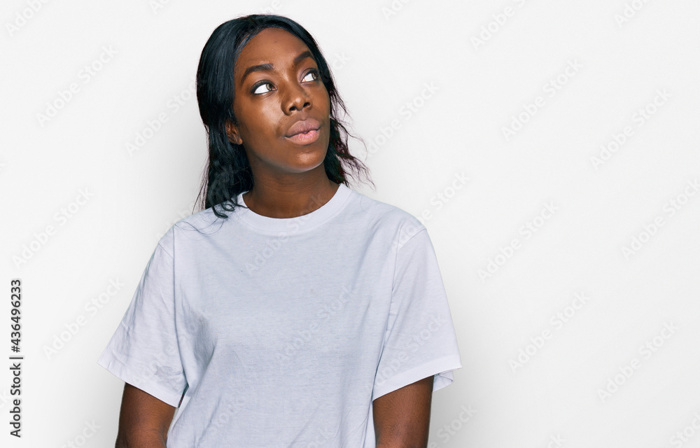 Young african american woman wearing casual white t shirt smiling looking to the side and staring away thinking. Young african american woman wearing casual white t shirt smiling looking to the side and staring away thinking.