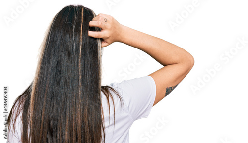 Young hispanic woman wearing casual white t shirt backwards thinking about doubt with hand on head