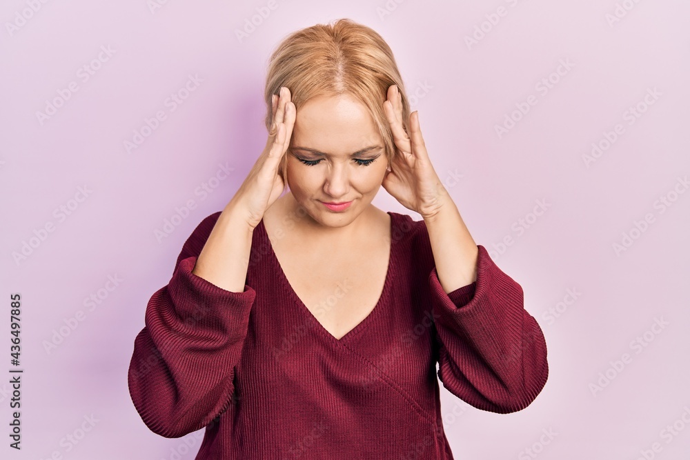 Young blonde woman wearing casual winter sweater with hand on head for pain in head because stress. suffering migraine. Young blonde woman wearing casual winter sweater with hand on head for pain in head because stress. suffering migraine.