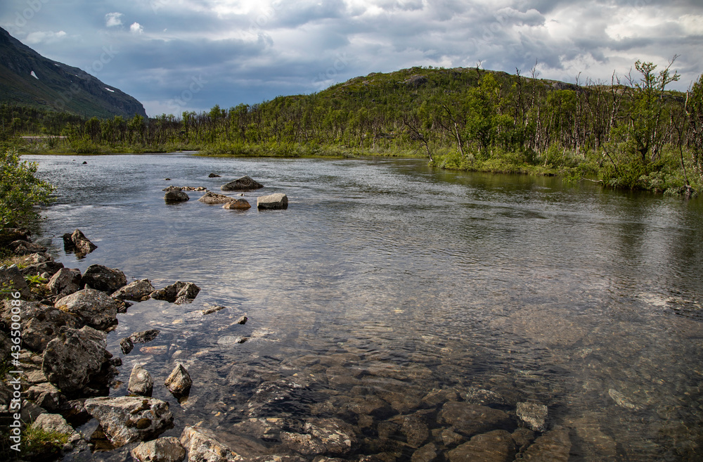 Northern Sweden. Rocky mountain river against the backdrop of sparse vegetation and cloudy sky