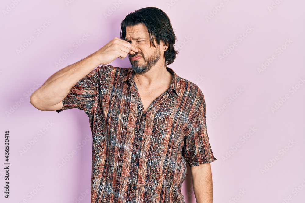 Middle age caucasian man wearing casual clothes smelling something stinky and disgusting, intolerable smell, holding breath with fingers on nose. bad smell Middle age caucasian man wearing casual clothes smelling something stinky and disgusting, intolerable smell, holding breath with fingers on nose. bad smell