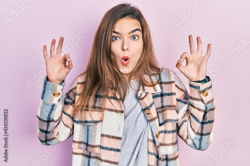 Young caucasian girl wearing casual clothes looking surprised and shocked doing ok approval symbol with fingers. crazy expression © Krakenimages.com