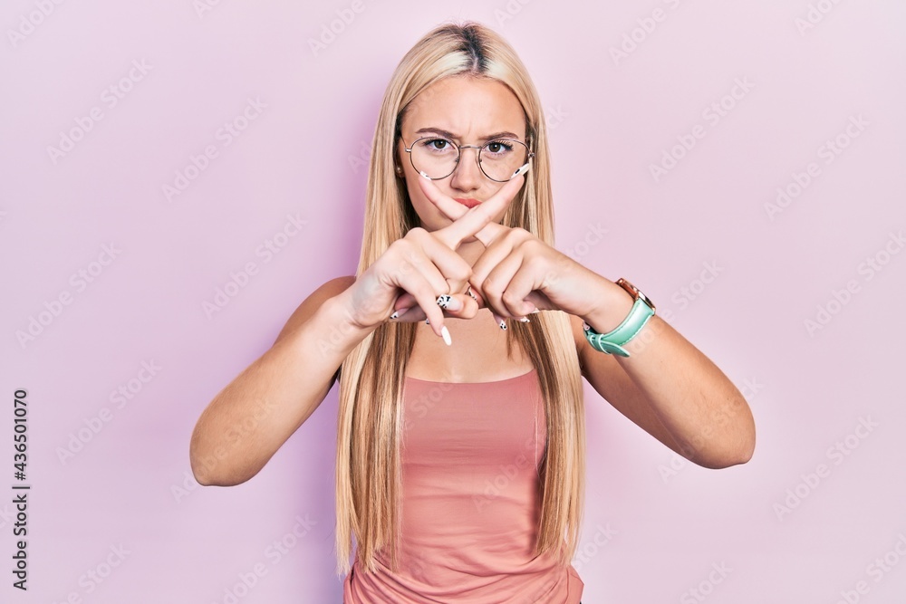 Young blonde girl wearing casual clothes rejection expression crossing fingers doing negative sign Young blonde girl wearing casual clothes rejection expression crossing fingers doing negative sign
