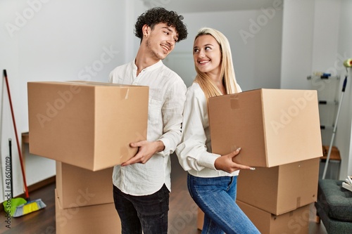 Young beautiful couple smiling happy holding cardboard box at new home. © Krakenimages.com