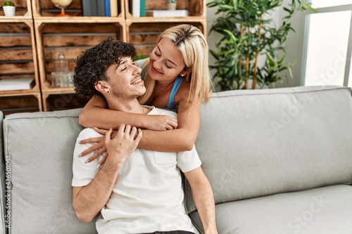 Young couple sitting on the sofa hugging at home.