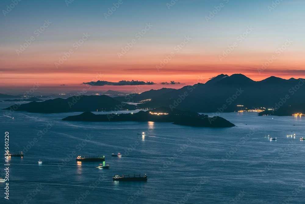 Stunning sunset in Hong Kong. Taken from West High Peak. Golden hour with ships and clouds. Wide angle sea view.