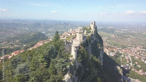 drone flying panoramic left around the city and close to san marino towers at the top of the mountain  in Italy