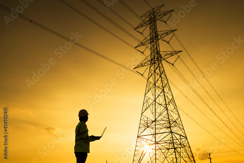 Engineer silhouette standing at power station planning work on power generation at high voltage electrodes.