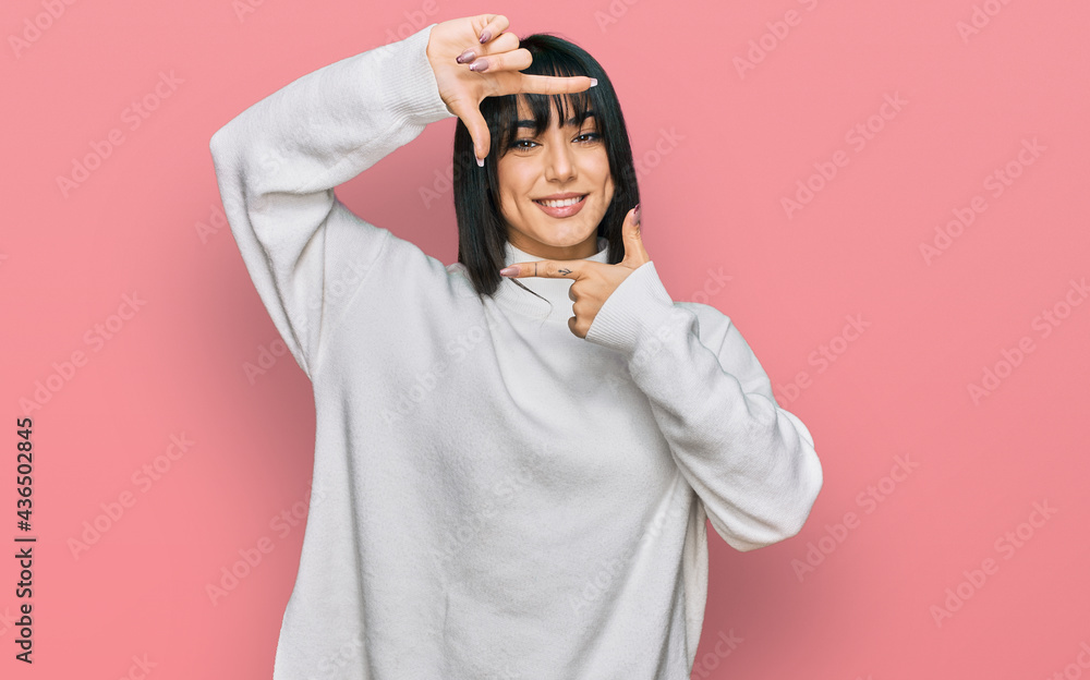 Young brunette woman with bangs wearing casual turtleneck sweater smiling making frame with hands and fingers with happy face. creativity and photography concept. Young brunette woman with bangs wearing casual turtleneck sweater smiling making frame with hands and fingers with happy face. creativity and photography concept.