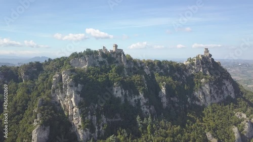 drone flying froward and panoramic left around the san marino towers at the top of the mountain  in Italy