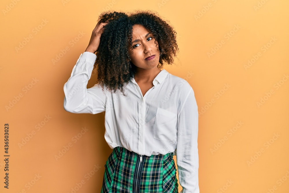 Beautiful african american woman with afro hair wearing scholar skirt confuse and wonder about question. uncertain with doubt, thinking with hand on head. pensive concept. Beautiful african american woman with afro hair wearing scholar skirt confuse and wonder about question. uncertain with doubt, thinking with hand on head. pensive concept.