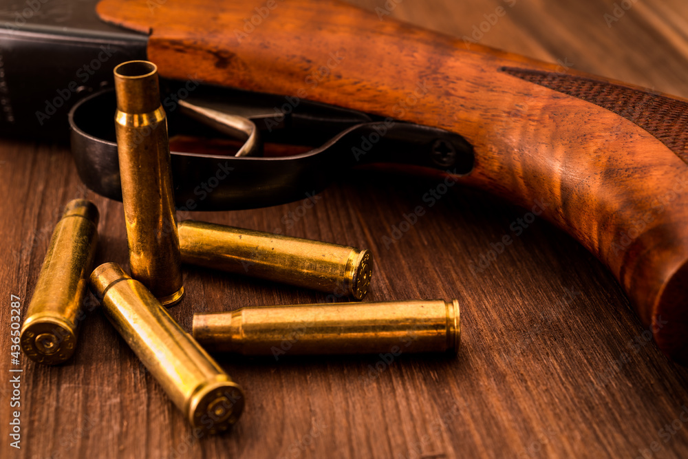 Fototapeta premium Rifle with empty shells lie on a wooden table