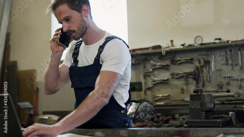 The worker speaks with his mobile phone in the workshop.pc, cell