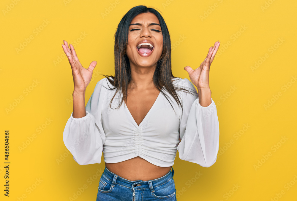 Young latin transsexual transgender woman wearing casual clothes celebrating mad and crazy for success with arms raised and closed eyes screaming excited. winner concept Young latin transsexual transgender woman wearing casual clothes celebrating mad and crazy for success with arms raised and closed eyes screaming excited. winner concept