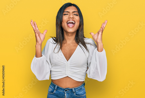 Young latin transsexual transgender woman wearing casual clothes celebrating mad and crazy for success with arms raised and closed eyes screaming excited. winner concept