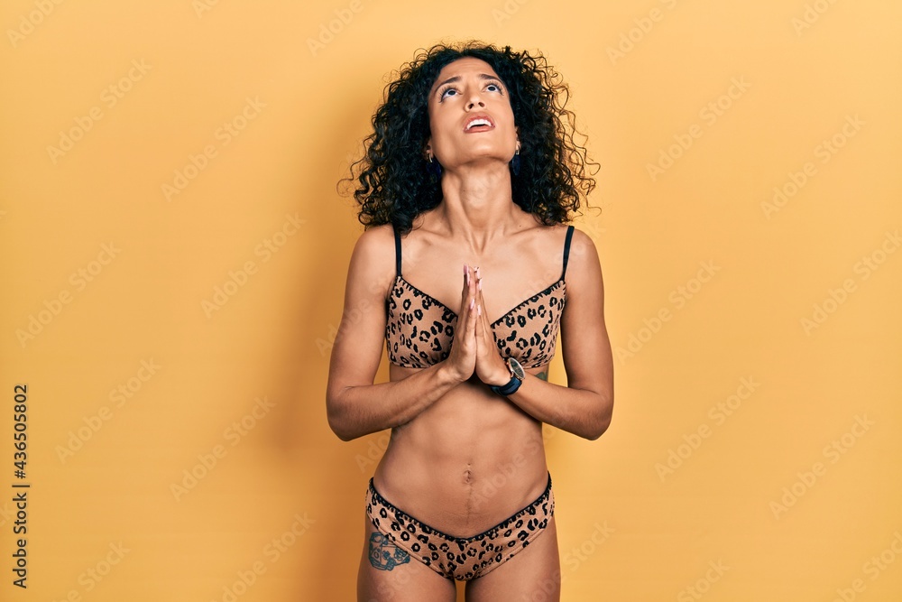 Young latin girl wearing bikini begging and praying with hands together with hope expression on face very emotional and worried. begging. Young latin girl wearing bikini begging and praying with hands together with hope expression on face very emotional and worried. begging.
