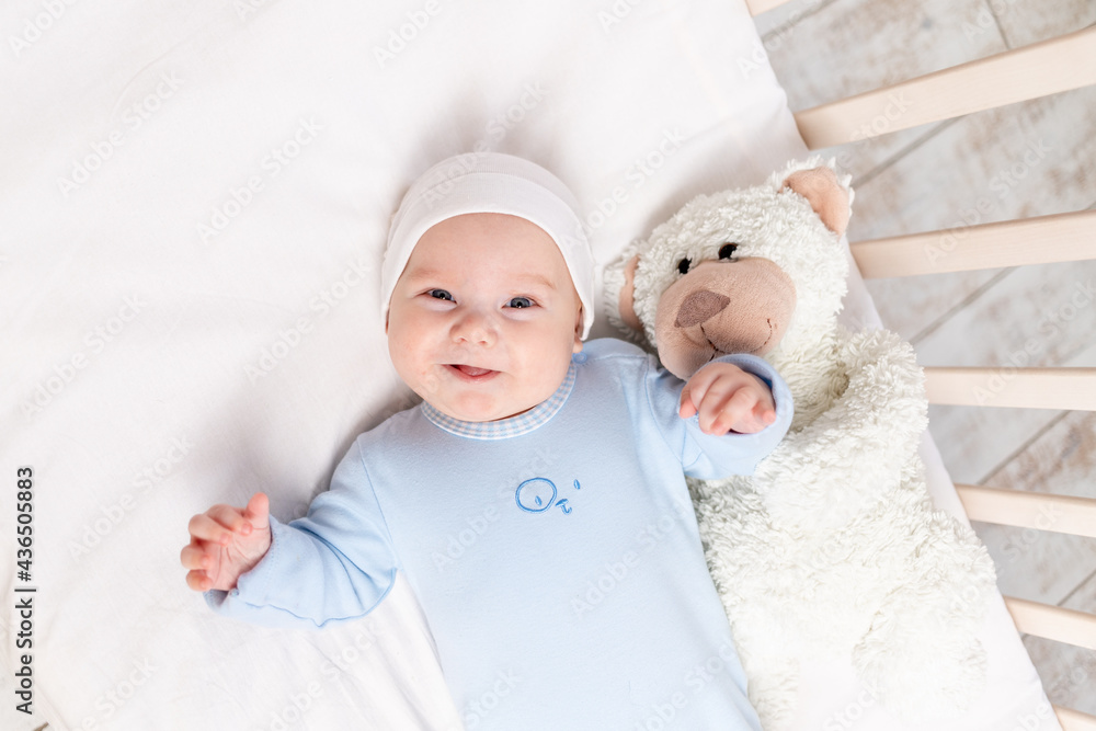 baby in the crib, portrait of a smiling baby 3 months in the crib with a teddy bear toy, children and birth concept baby in the crib, portrait of a smiling baby 3 months in the crib with a teddy bear toy, children and birth concept