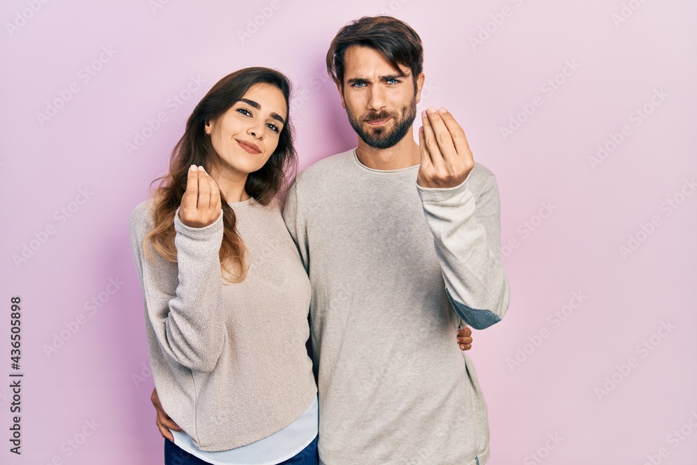 Young hispanic couple wearing casual clothes doing money gesture with hands, asking for salary payment, millionaire business Young hispanic couple wearing casual clothes doing money gesture with hands, asking for salary payment, millionaire business