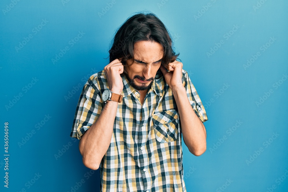 Young hispanic man wearing casual clothes covering ears with fingers with annoyed expression for the noise of loud music. deaf concept. Young hispanic man wearing casual clothes covering ears with fingers with annoyed expression for the noise of loud music. deaf concept.