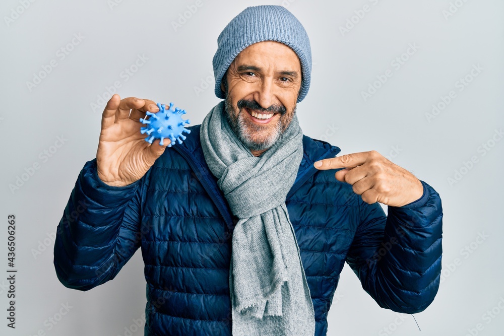 Middle age hispanic man wearing winter style holding virus toy pointing finger to one self smiling happy and proud Middle age hispanic man wearing winter style holding virus toy pointing finger to one self smiling happy and proud