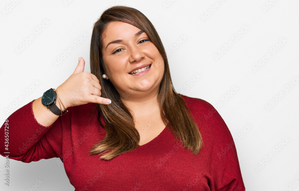 Beautiful brunette plus size woman wearing casual clothes smiling doing phone gesture with hand and fingers like talking on the telephone. communicating concepts. Beautiful brunette plus size woman wearing casual clothes smiling doing phone gesture with hand and fingers like talking on the telephone. communicating concepts.