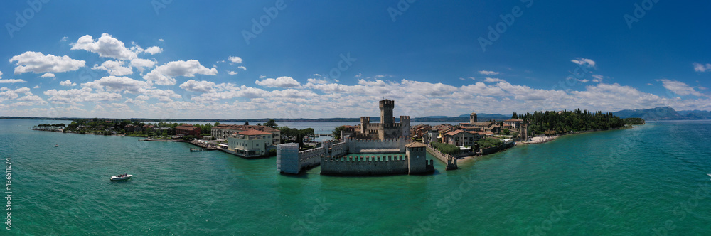 Aerial Panorama of the island of Sirmione. Sirmione, Lake Garda, Italy. Peninsula on a mountain lake in the background of the alps. Castle on the water in Italy.