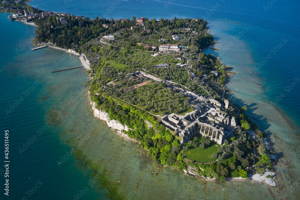 Aerial view of the Grotte di Catullo Ruins at high altitude. Grottoes ruins on the Sirmione peninsula. Olive grove and archaeological museum. Lake Garda, Italy.