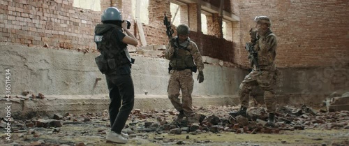 Two soldiers posing for female war journalist inside destroyed building. Shot with 2x anamorphic lens photo