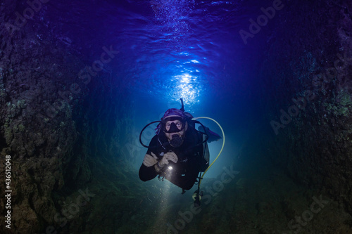 A male scuba diver in the ocean at night. The shot is backlit to create an interesting effect