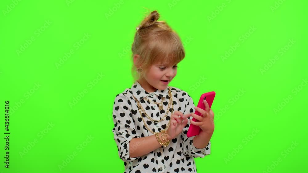 Portrait of blonde kid child looking smartphone display sincerely rejoicing win, receiving message with good news, success luck. Teenager children girl with mobile phone on chroma key green background Portrait of blonde kid child looking smartphone display sincerely rejoicing win, receiving message with good news, success luck. Teenager children girl with mobile phone on chroma key green background