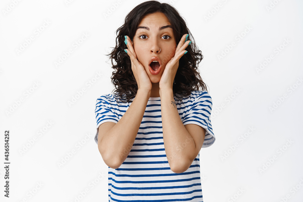 Surprised brunette girl look with amazement at camera, watching something impressive, gasping and say wow, staring astonished, white background Surprised brunette girl look with amazement at camera, watching something impressive, gasping and say wow, staring astonished, white background