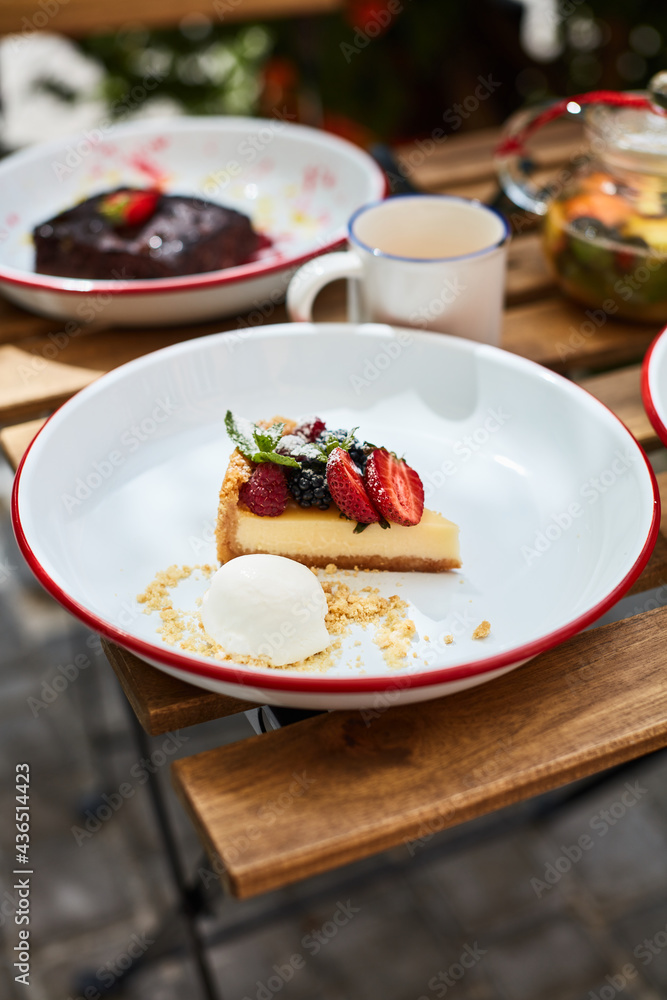 cheesecake with strawberries and ice cream in a plate on the table with other desserts