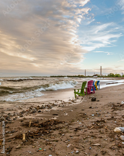 Photography Toronto Beaches sunset with waves breaking on the sand and colorful plastic muskoka chairs in the surf, seen from Kew Beach in Toronto's east end