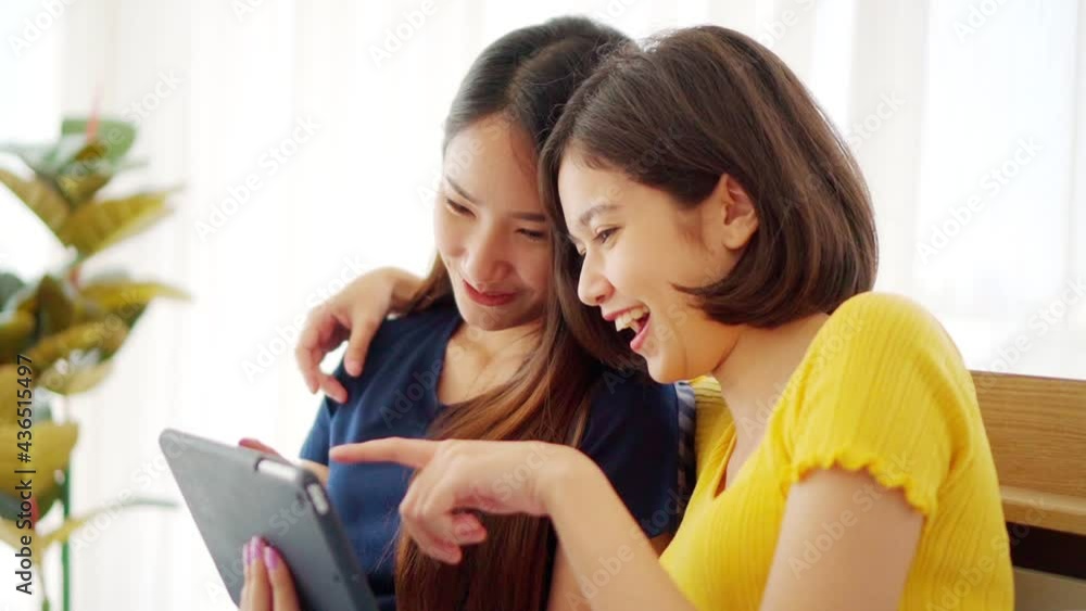 Slow motion Young beautiful Asian couple love friend woman looking at tablet and touch hand on bedroom at home which smiling and felling happy, LGBT woman love Travelling summer vacation trip concept Slow motion Young beautiful Asian couple love friend woman looking at tablet and touch hand on bedroom at home which smiling and felling happy, LGBT woman love Travelling summer vacation trip concept