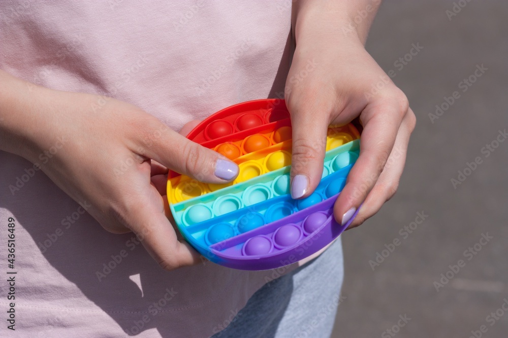 Pop it anti stress toy in young caucasian woman hands outdoors. New 2021 Tiktok trend.