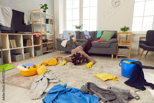Принти на полотні Miserable tired housewife fallen on floor while cleaning up crazy mess in her house