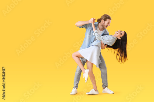 Happy young couple dancing on color background