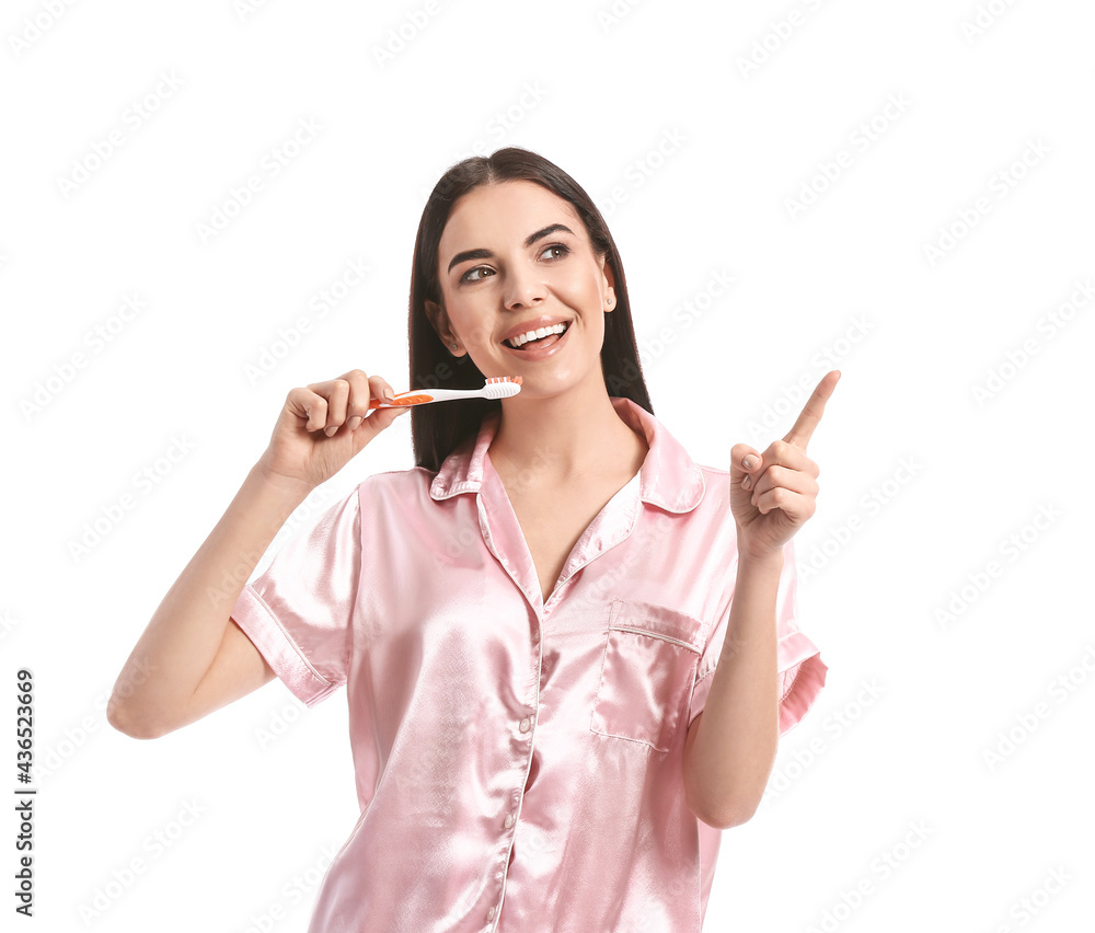 Young woman brushing teeth and pointing at something on white background Young woman brushing teeth and pointing at something on white background