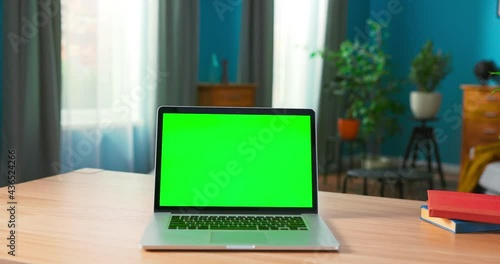 Laptop with Green Mock up Screen on a desk in a cozy living room at home. photo